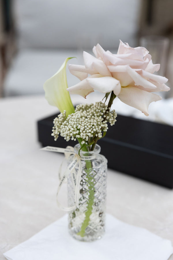 Bud vase with a blush rose and calla lily on a table at a local business