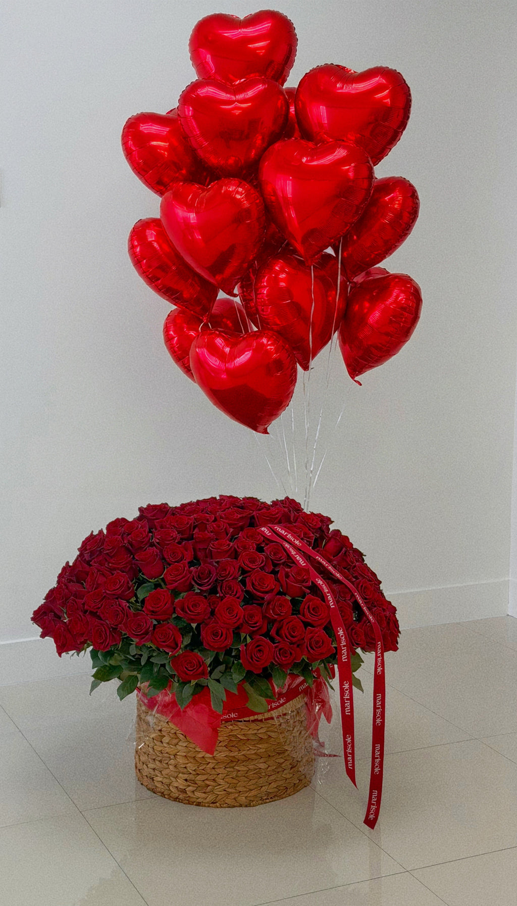 Bouquet of red roses and heart-shaped balloons on a light background