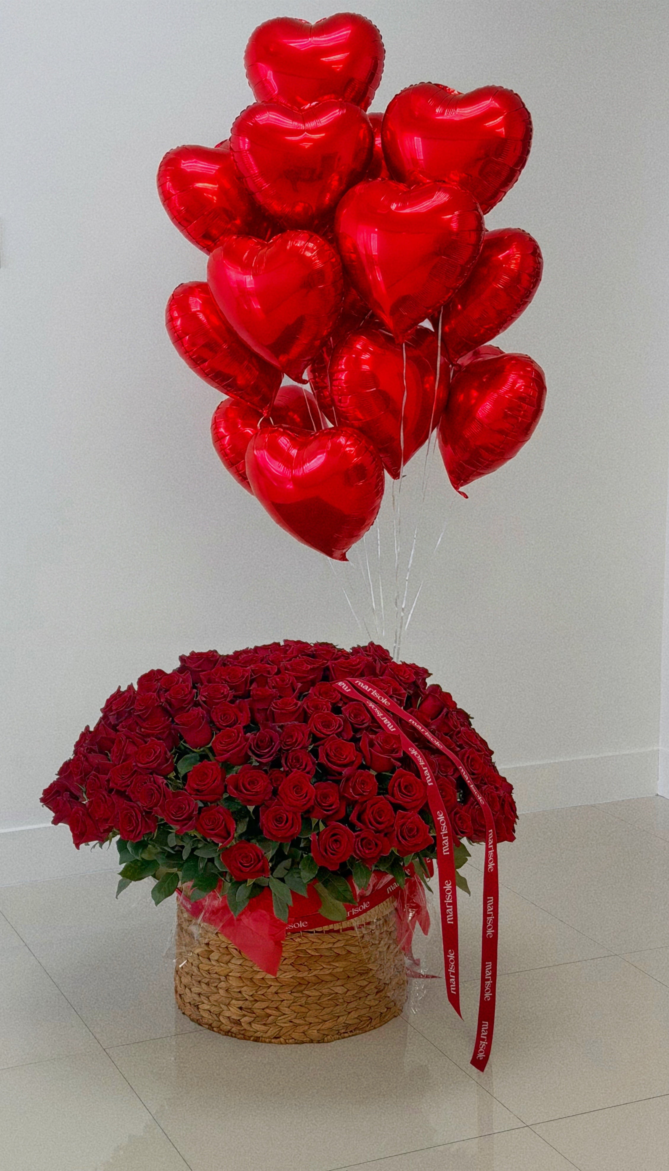 Bouquet of red roses and heart-shaped balloons on a light background