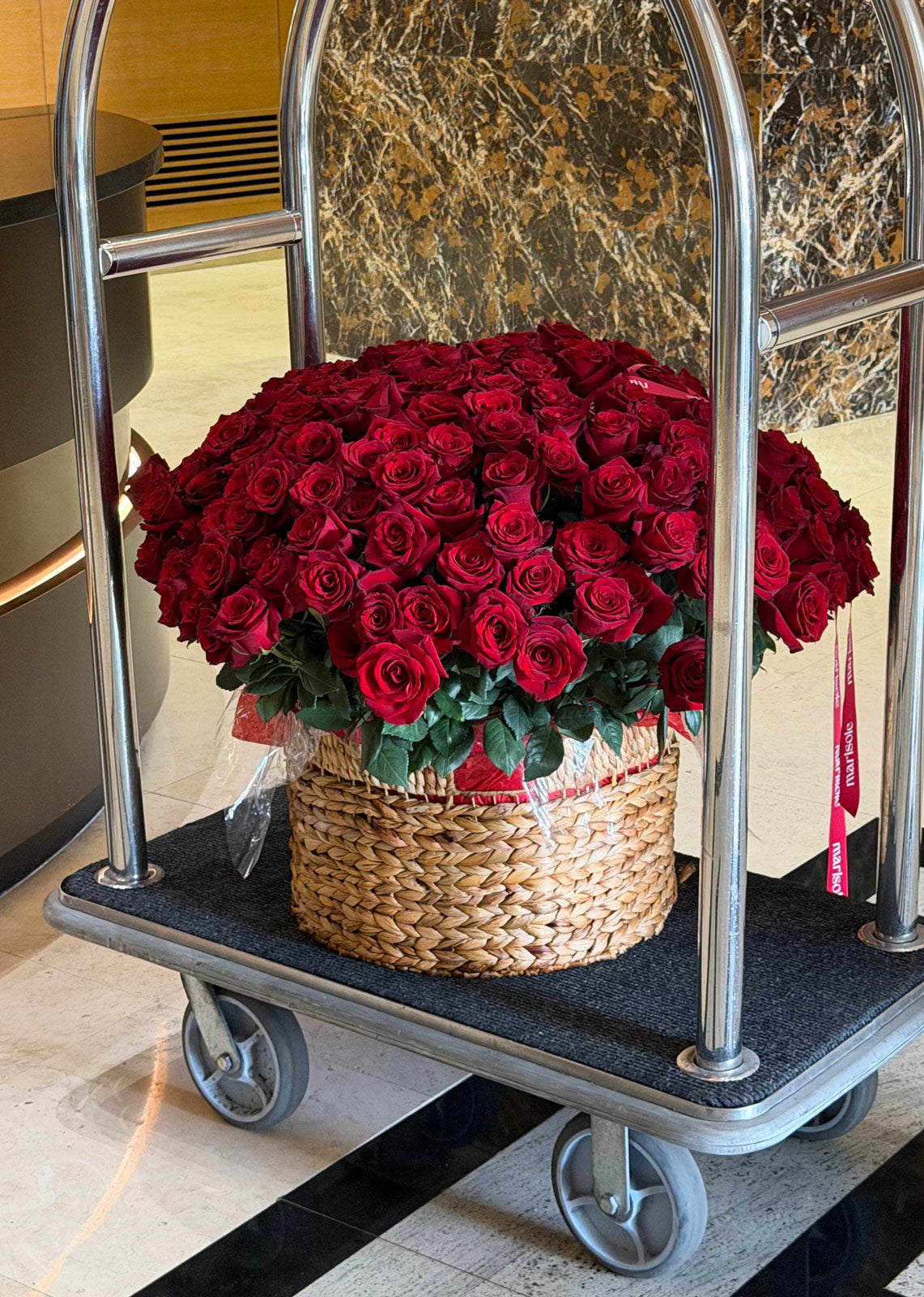 Basket of red roses on a metal trolley in a marble hallway