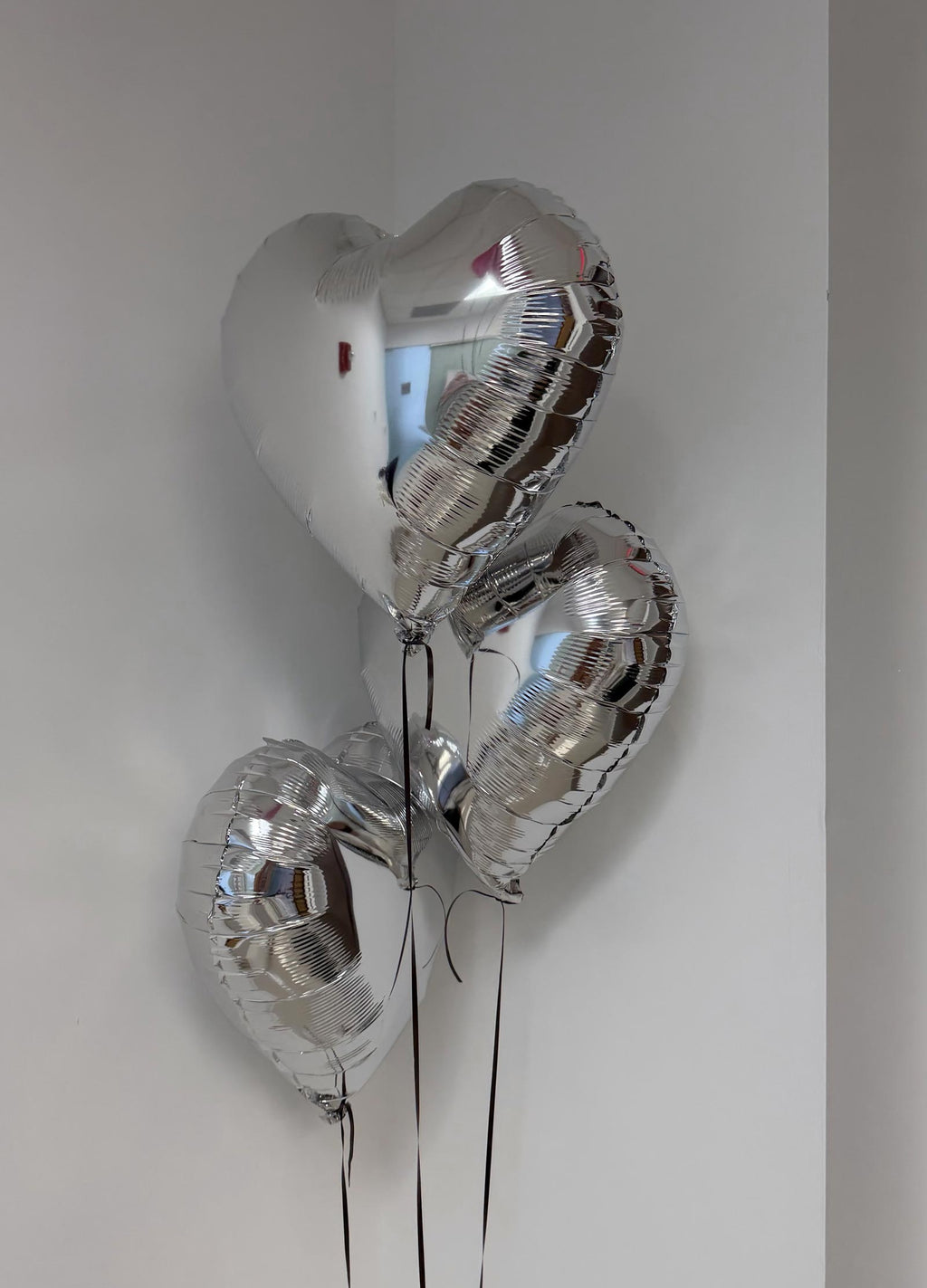 3 Silver heart-shaped balloons against a plain background