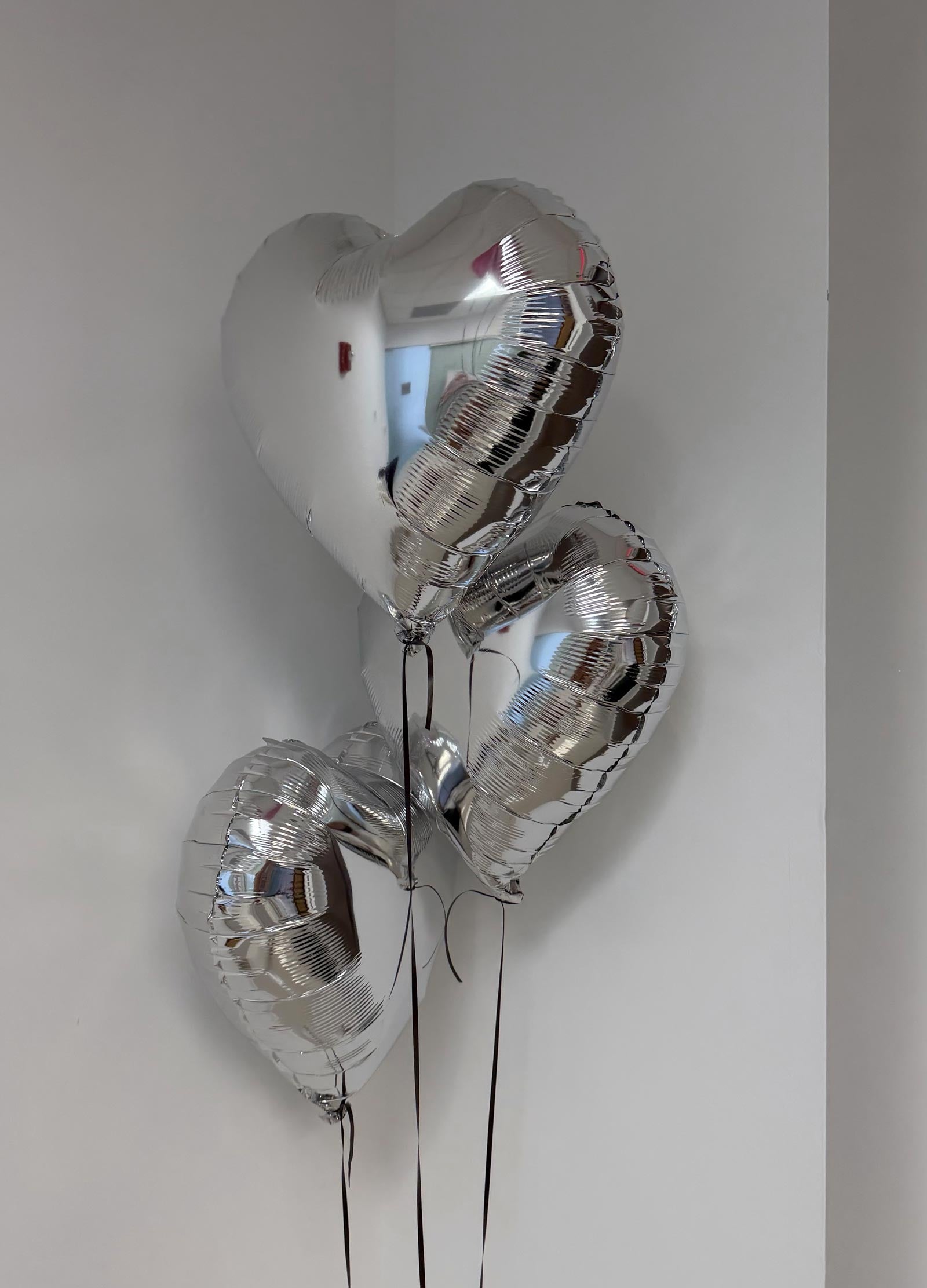 3 Silver heart-shaped balloons against a plain background