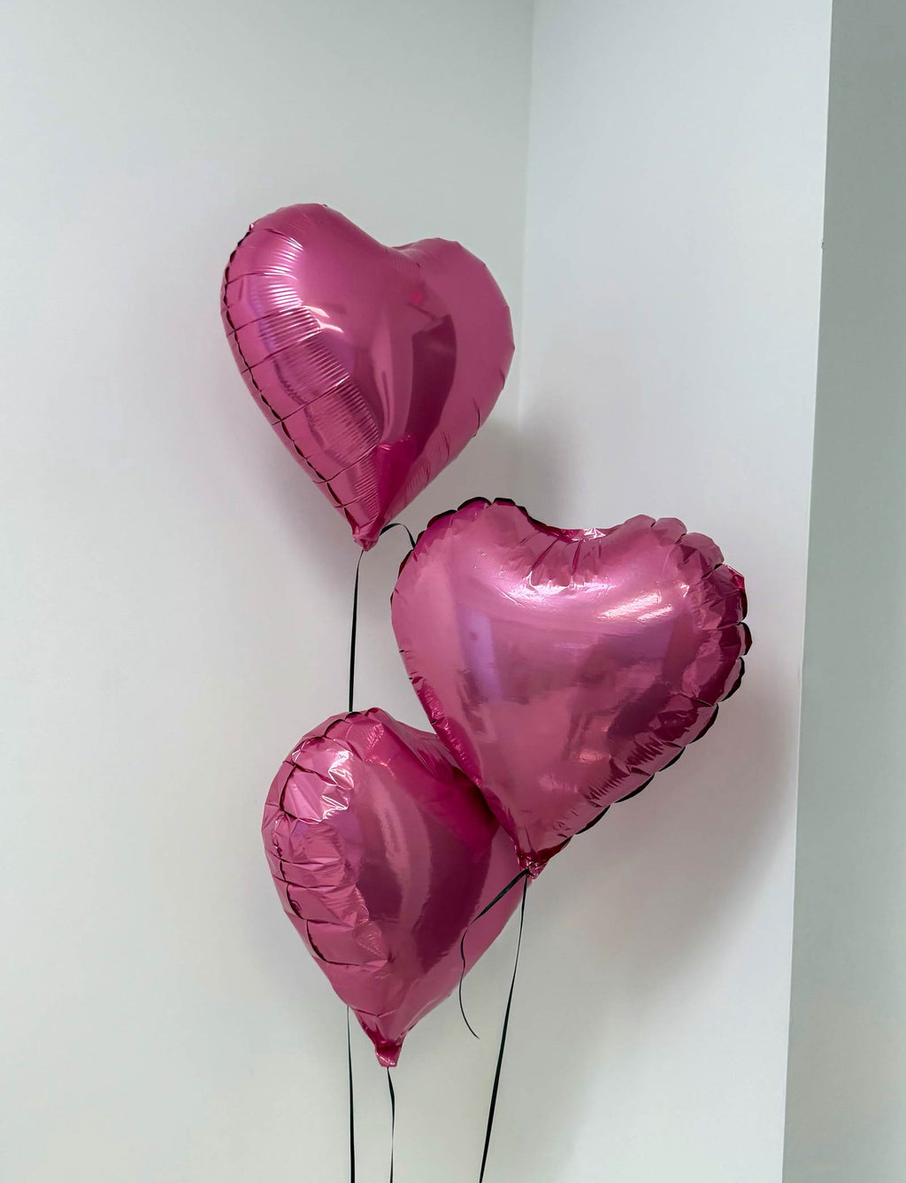 Three pink heart-shaped balloons on a white background