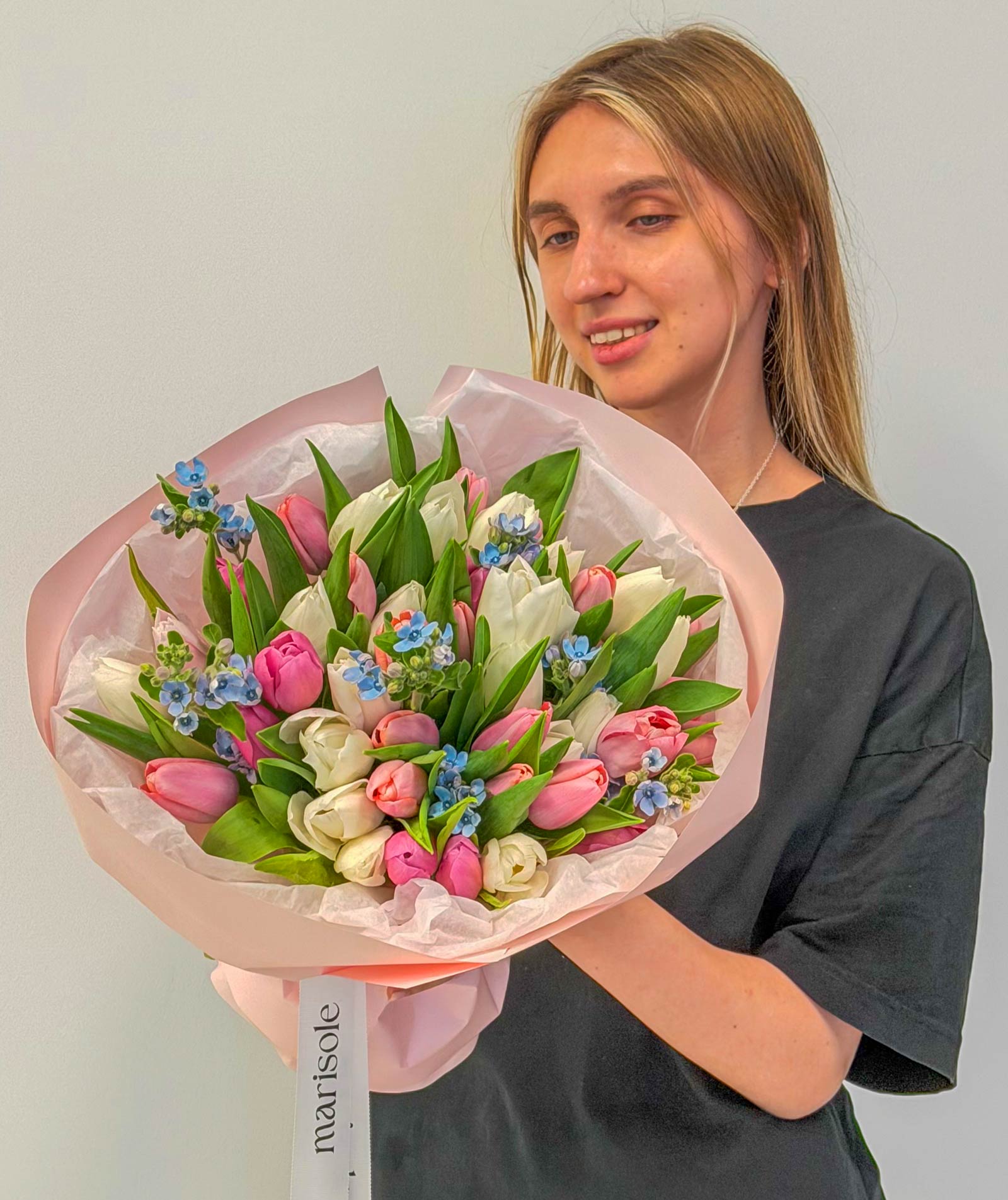 Person holding a bouquet of flowers with a plain background