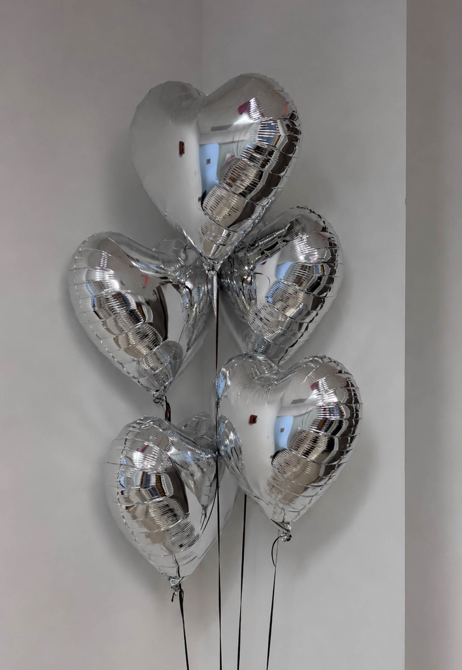 5 Silver heart-shaped balloons against a plain background