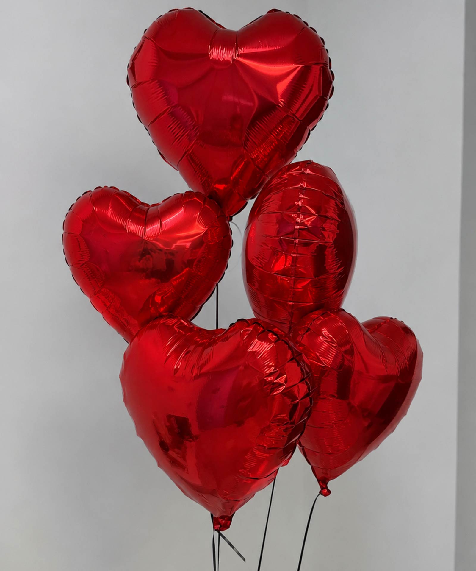 5 red heart-shaped balloons on a gray background