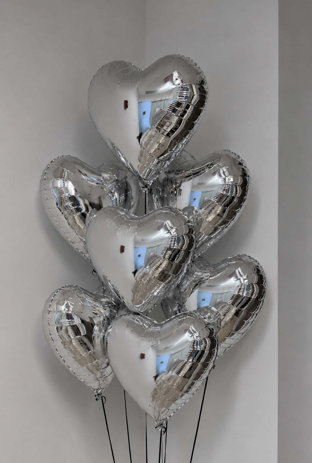 7 Silver heart-shaped balloons against a plain background