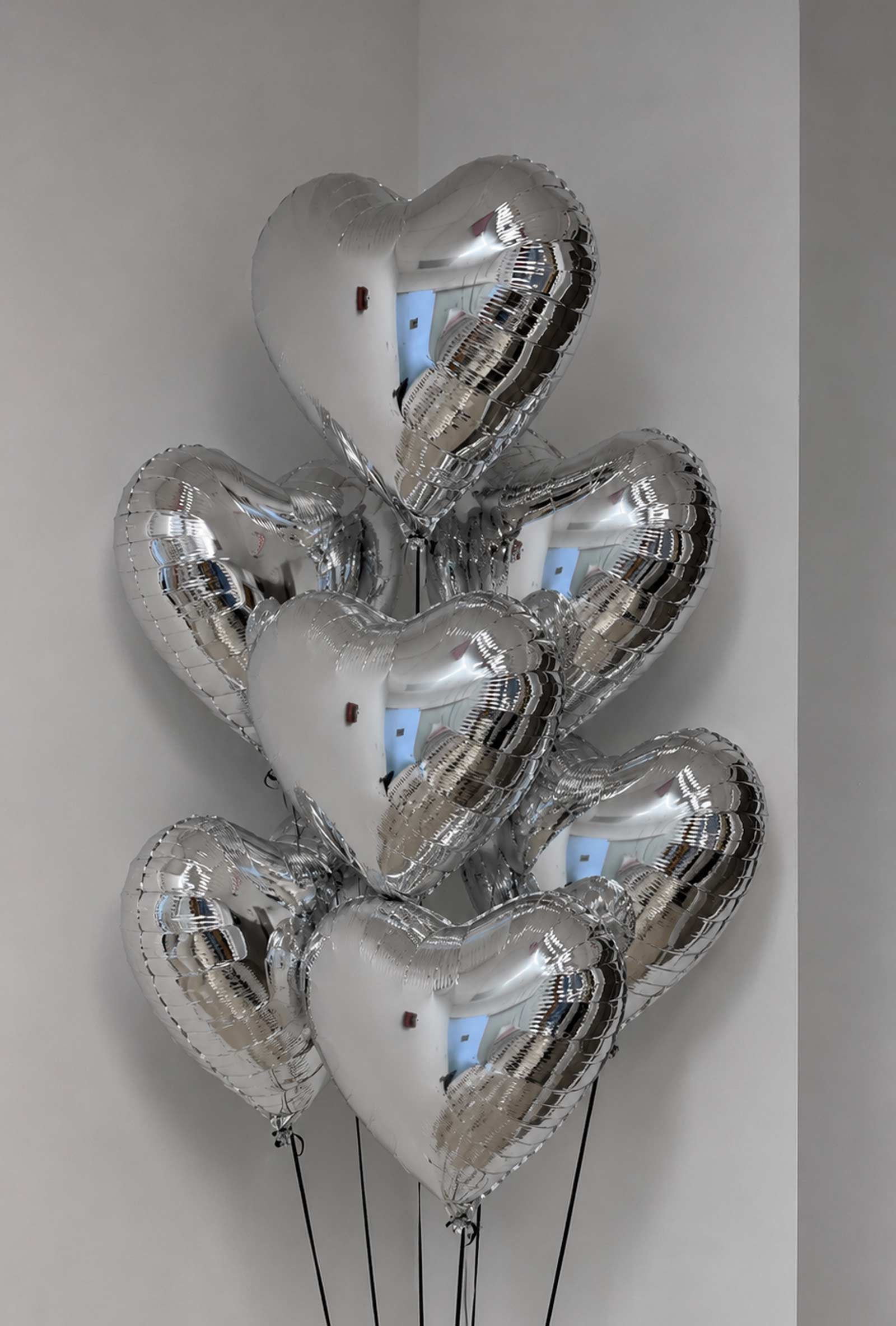 7 Silver heart-shaped balloons against a plain background