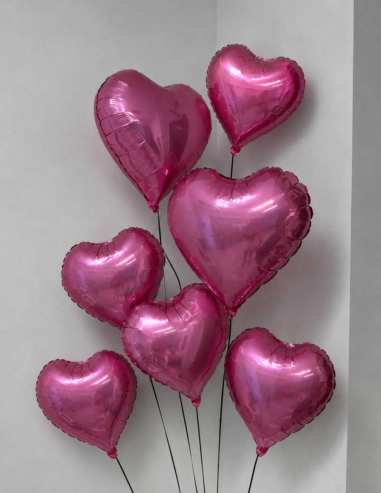 7 Pink heart-shaped balloons on a white background