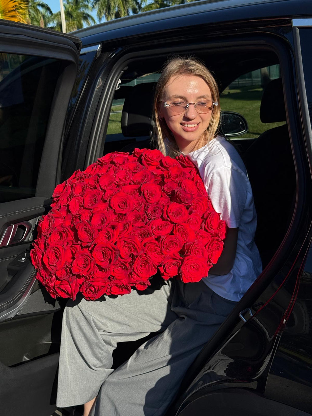 Person holding a large bouquet of red roses sitting in a car
