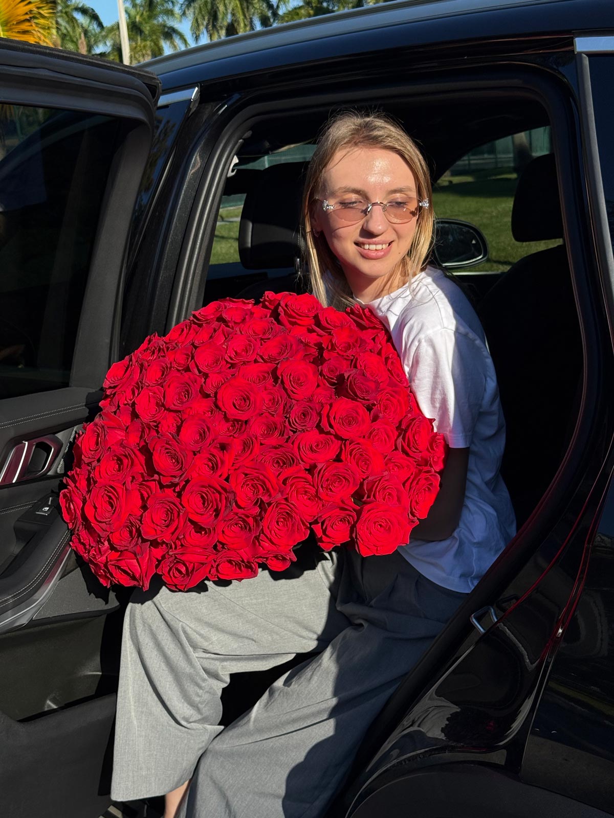 Person holding a large bouquet of red roses sitting in a car
