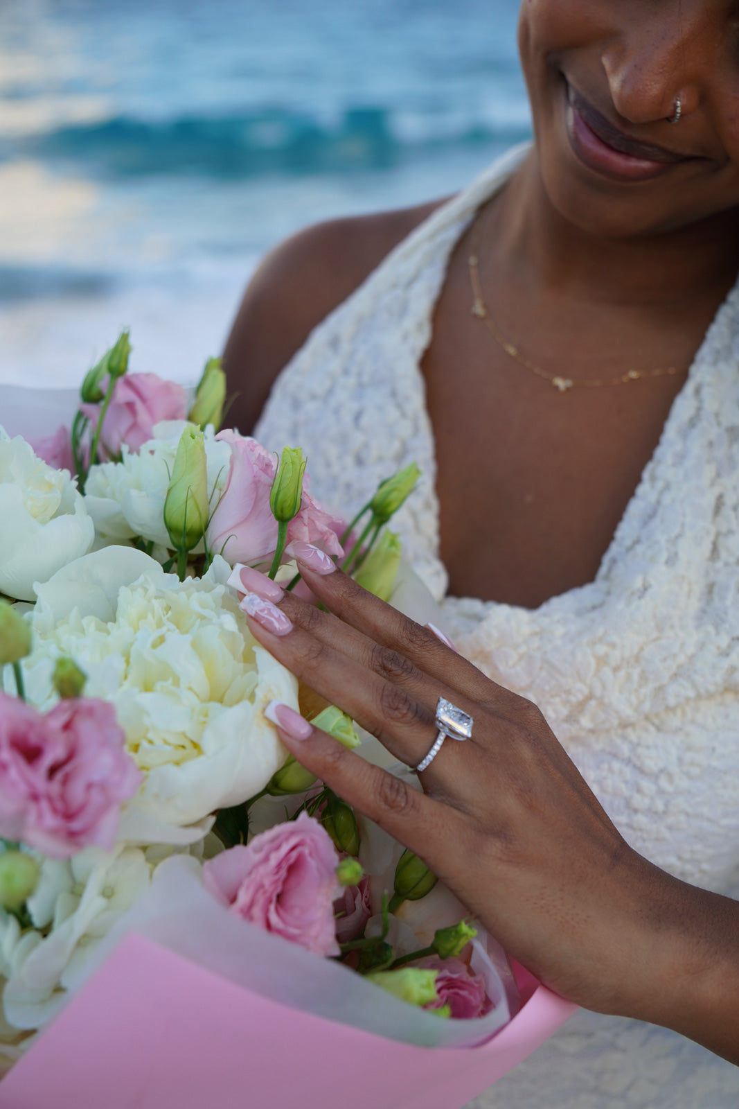Woman holding a bouquet of flowers with a blurred beach background