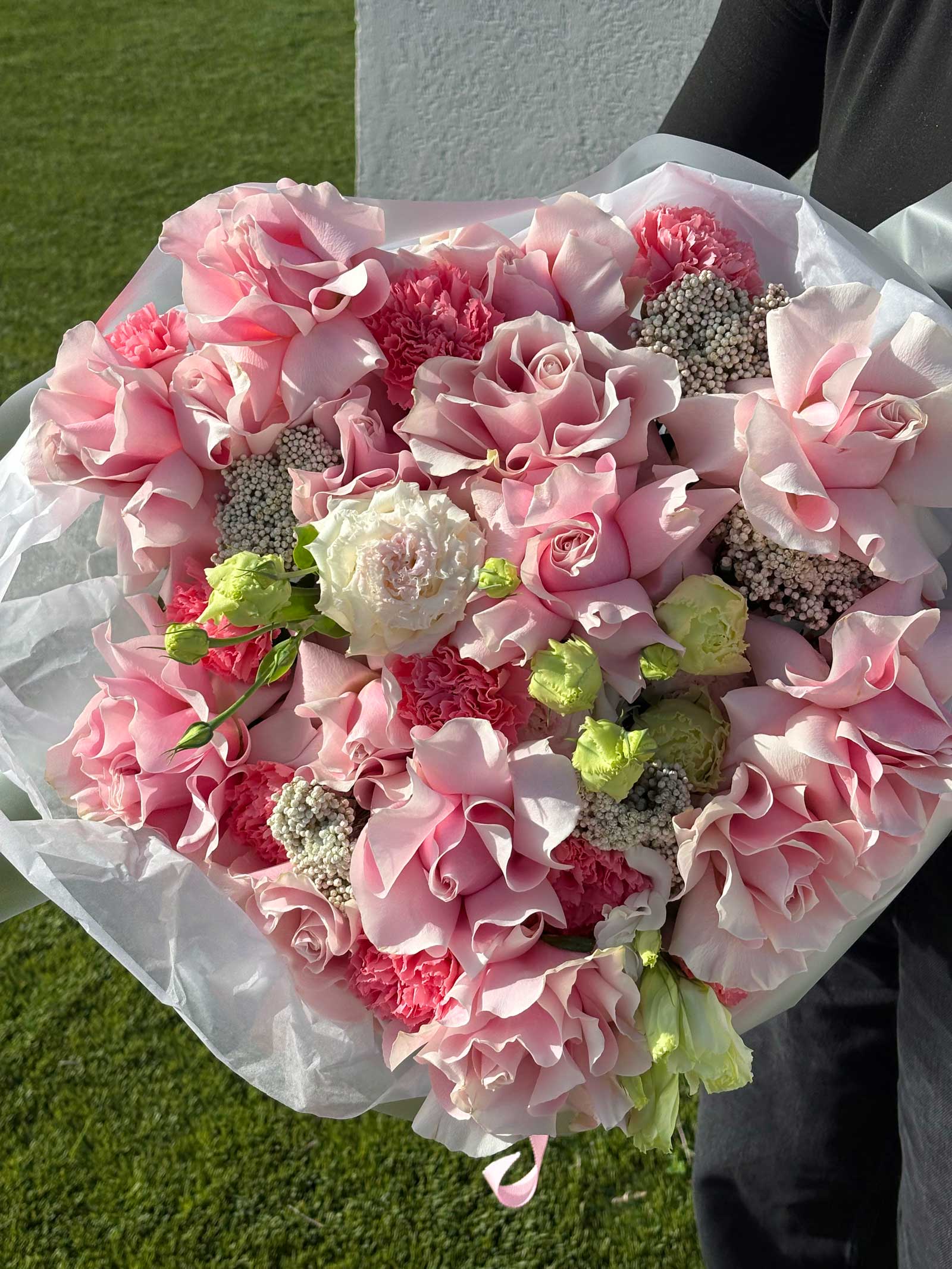 Heart-shaped bouquet of pink and white flowers on a grassy background
