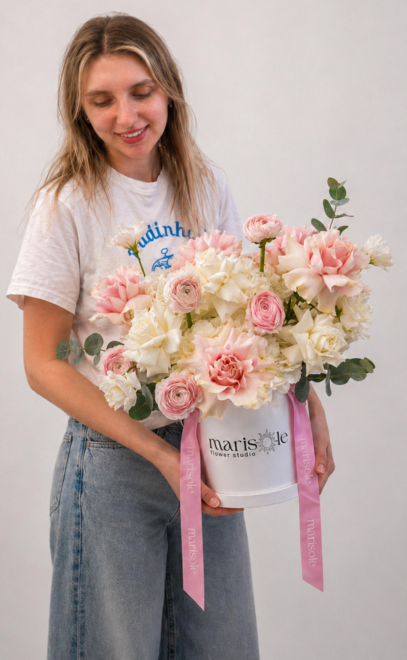 Woman holding a bouquet of flowers with a pink ribbon, against a plain background
