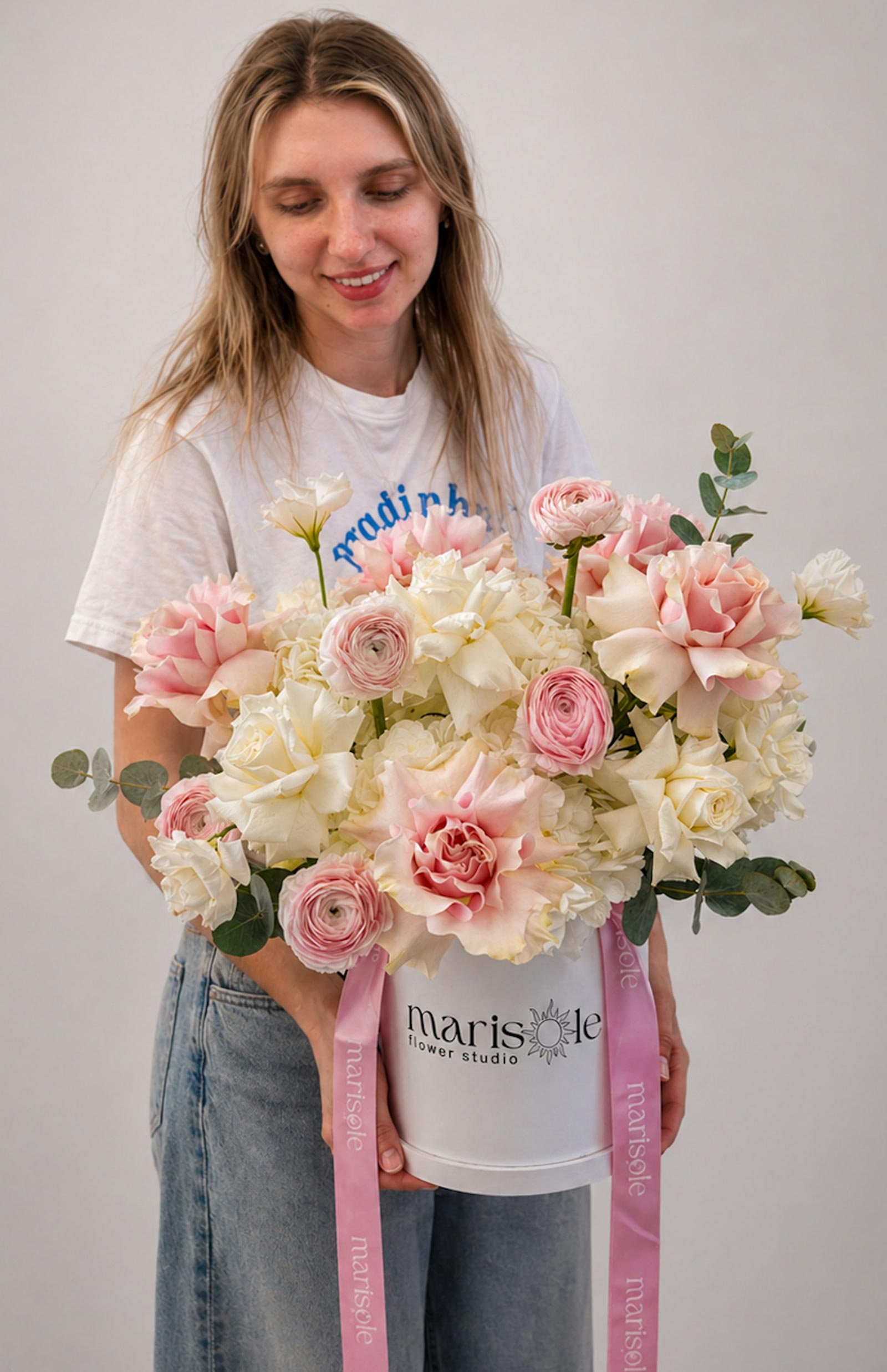 Person holding a large bouquet of flowers with visible branding on a plain background