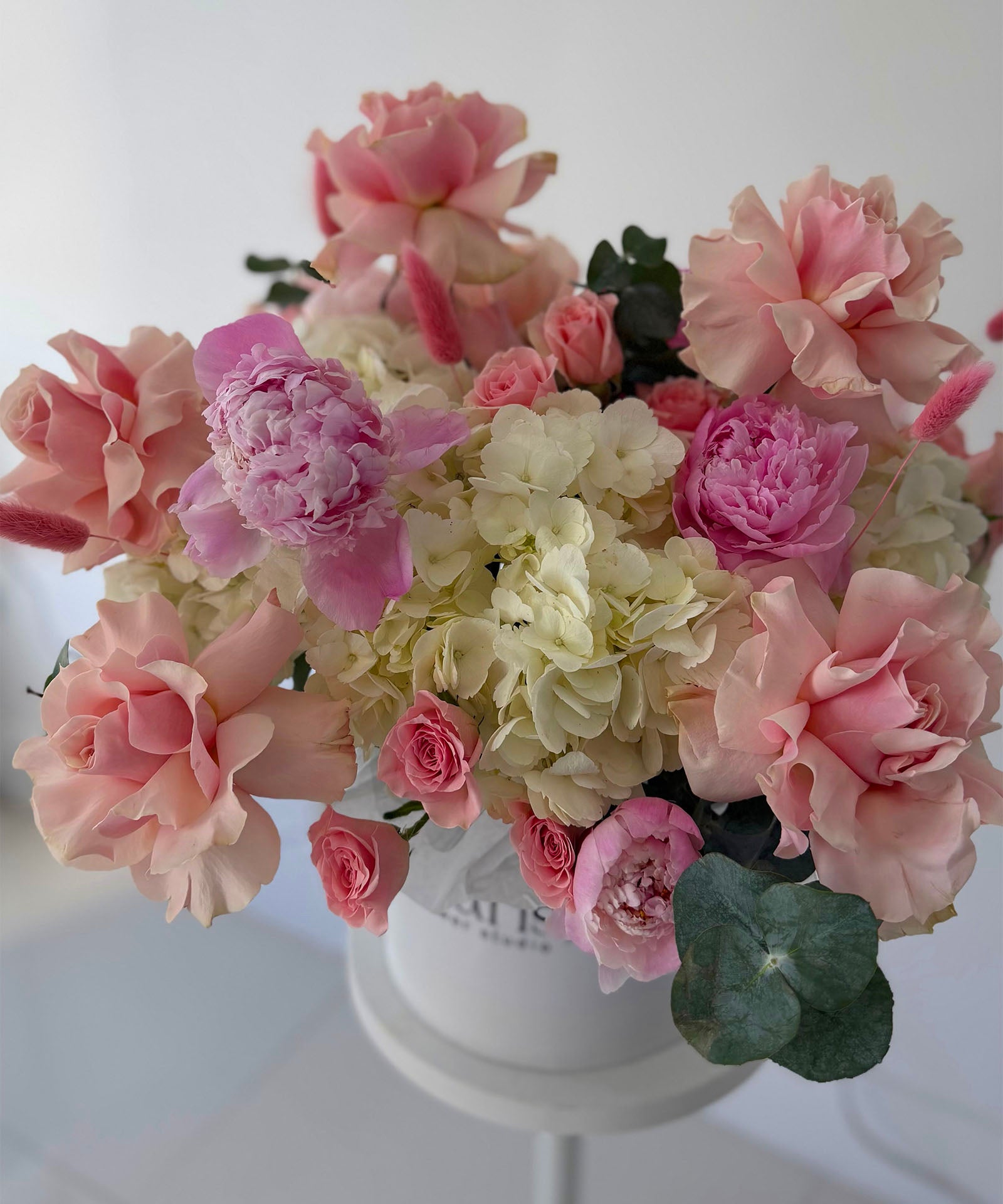 Bouquet of pink and white flowers in a white pot on a light background