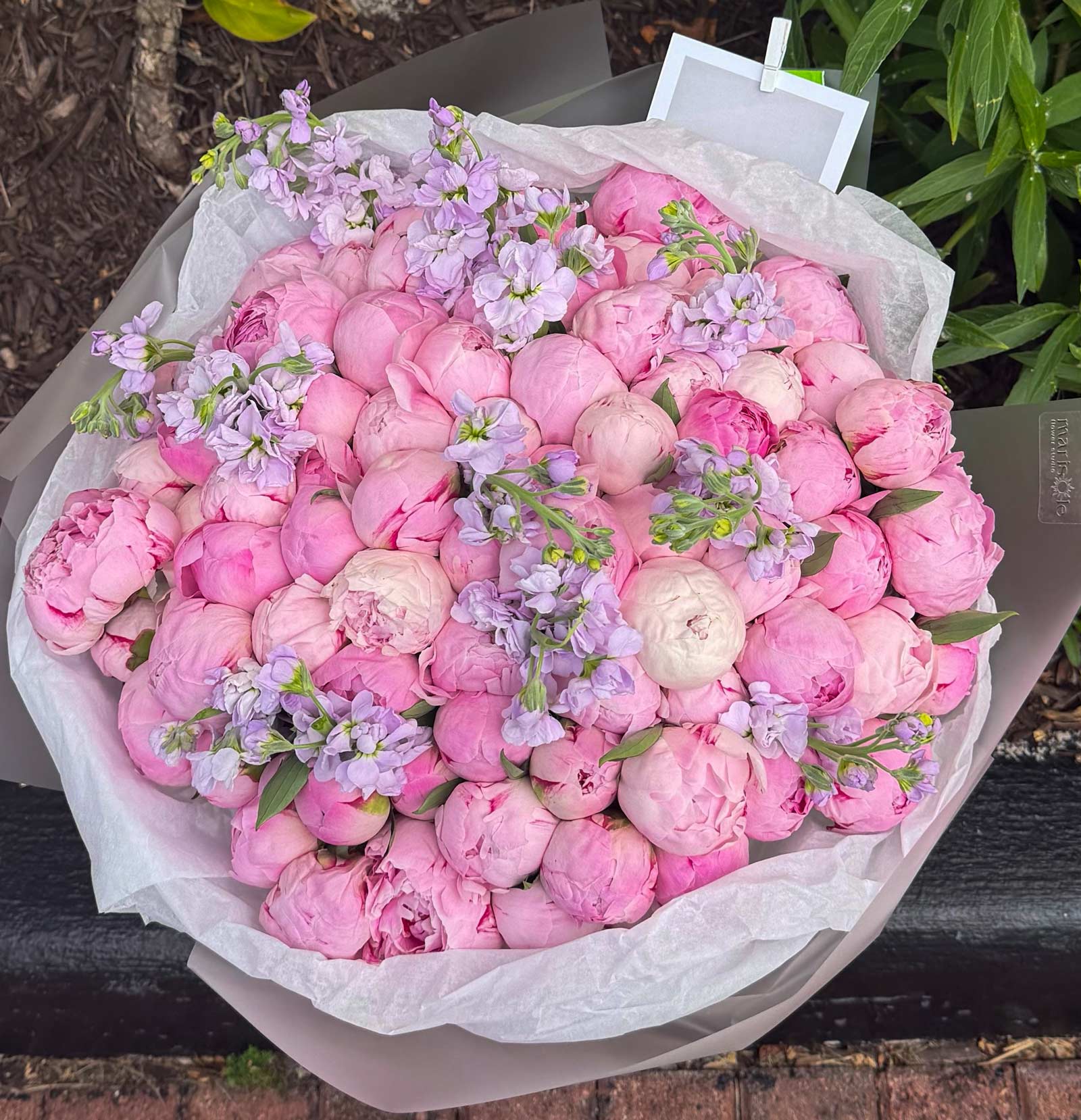 Bouquet of pink and white flowers with greenery on a wooden surface.