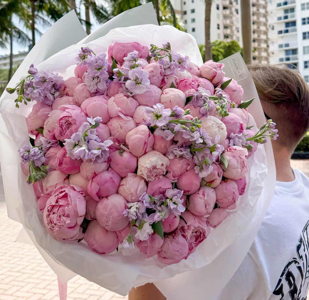 Bouquet of pink flowers with a person holding it outdoors.