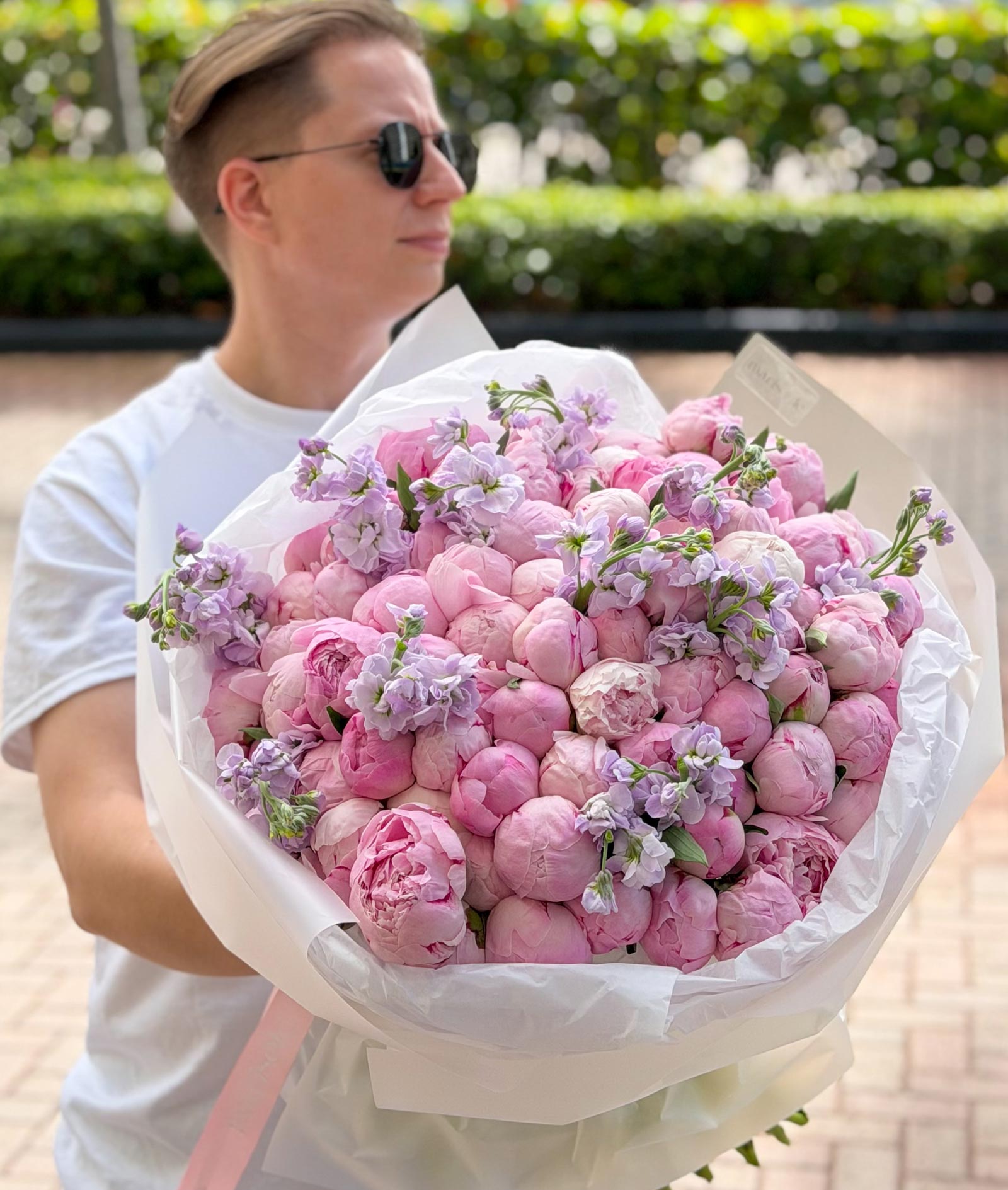 Pink bouquet of peonies and stock wrapped in white paper, featuring Marisole Flower Studio styling.