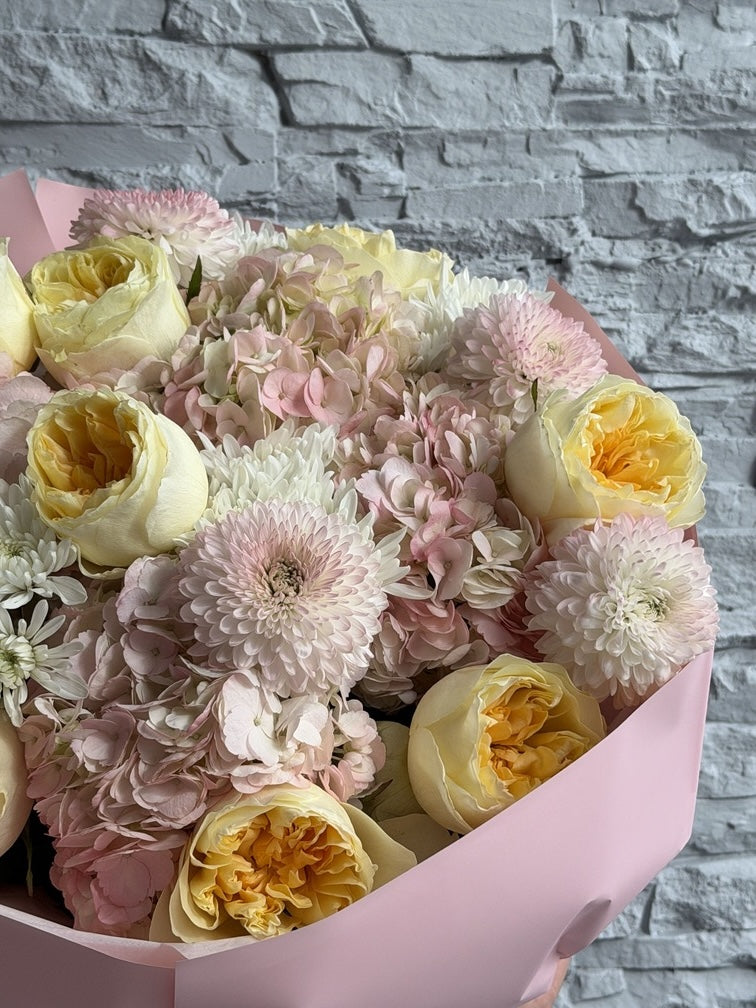 Bouquet of flowers in a pink box against a stone wall background