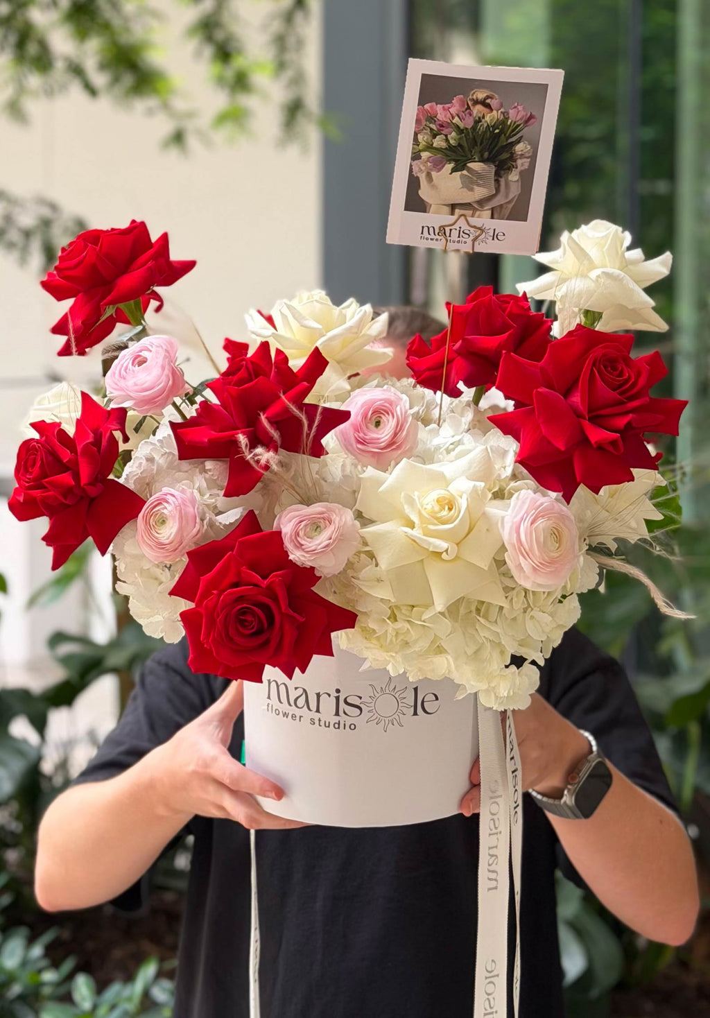 Person holding the Bordeaux & Blanc Box with red French Roses, white blooms, blush ranunculus, and hydrangea in a Marisole Flower Studio box.