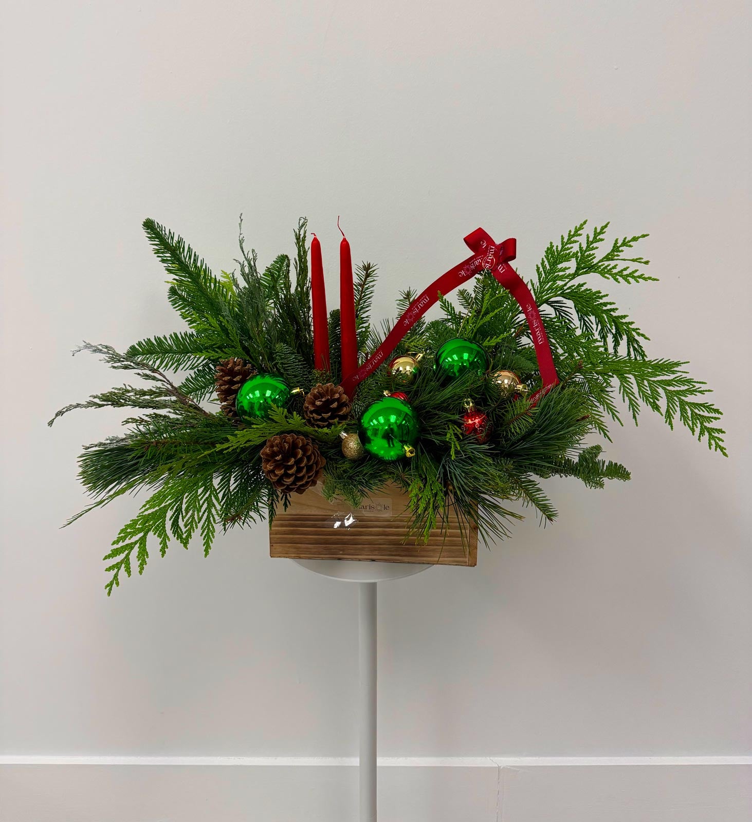 Decorative Christmas arrangement with greenery, candles, and ornaments on a white background