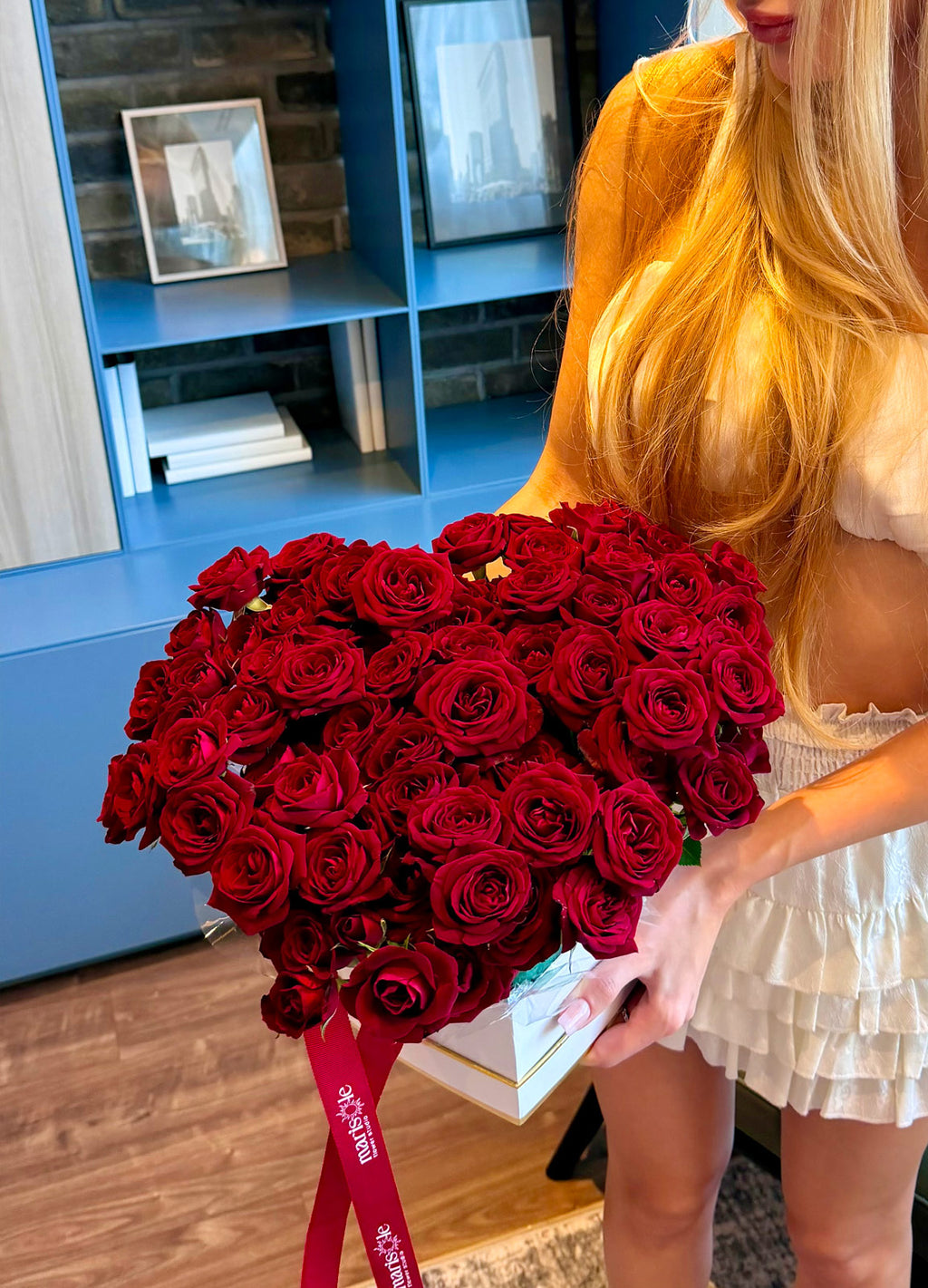 Person holding a large bouquet of red roses indoors.