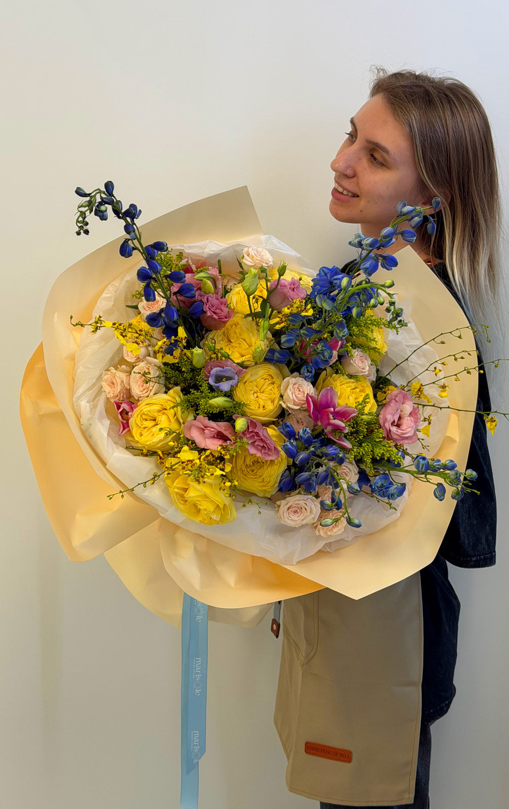 Person holding a large bouquet of flowers against a plain background