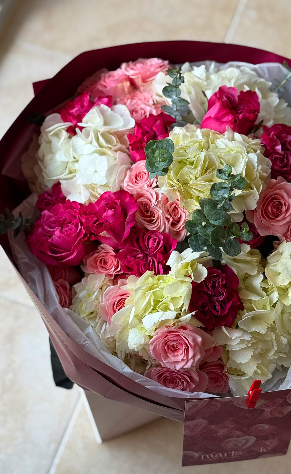 Bouquet of pink, white, and red flowers in a box on a light background
