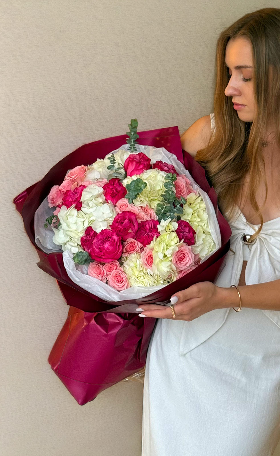 Woman holding a bouquet of flowers against a plain background