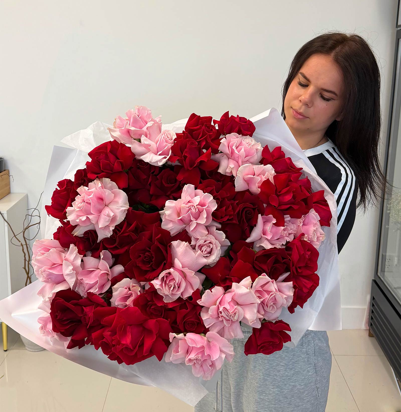 Person holding a large bouquet of red and pink french roses