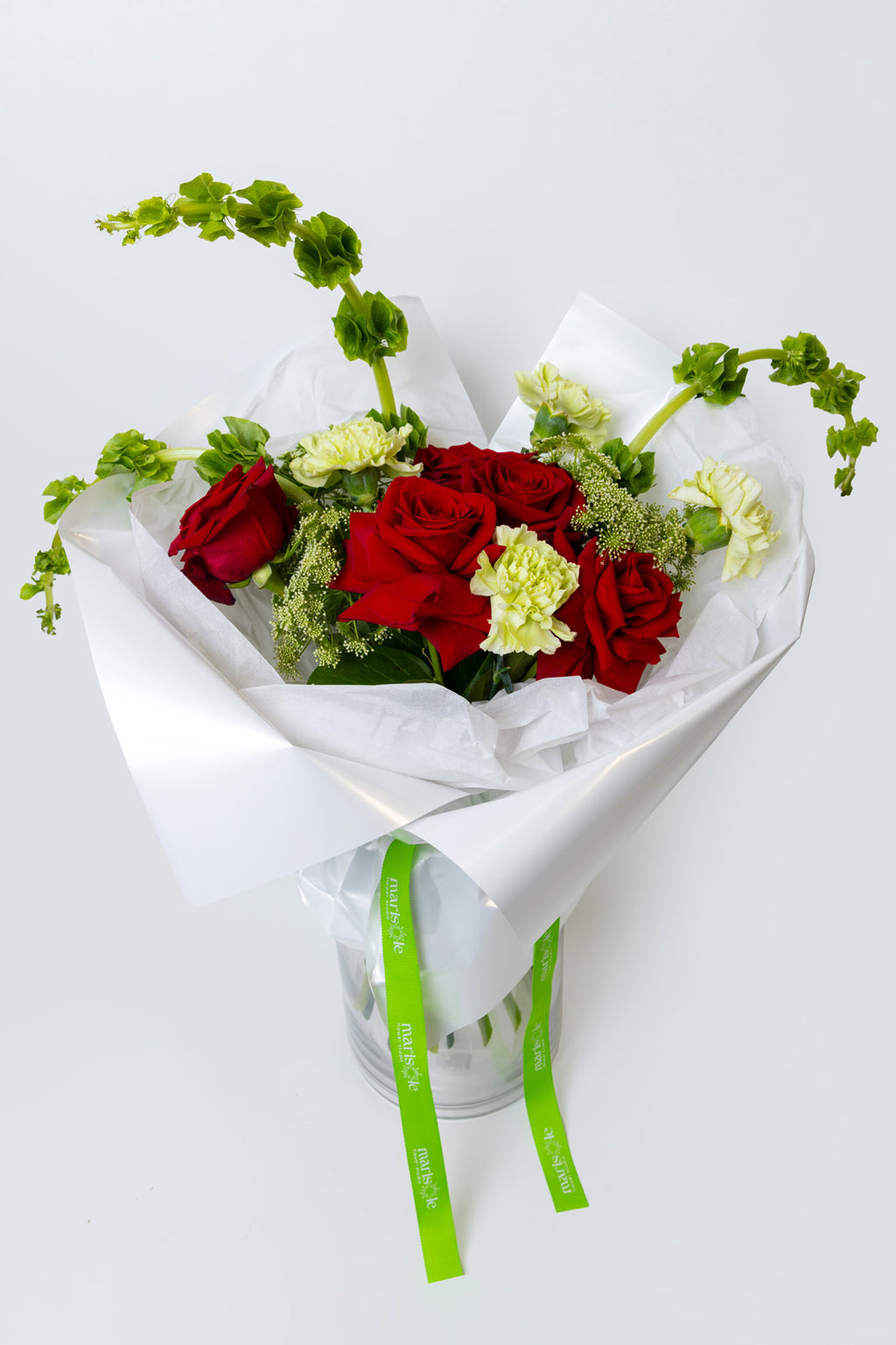 Bouquet of red and green flowers wrapped in white paper with a green ribbon on a white background