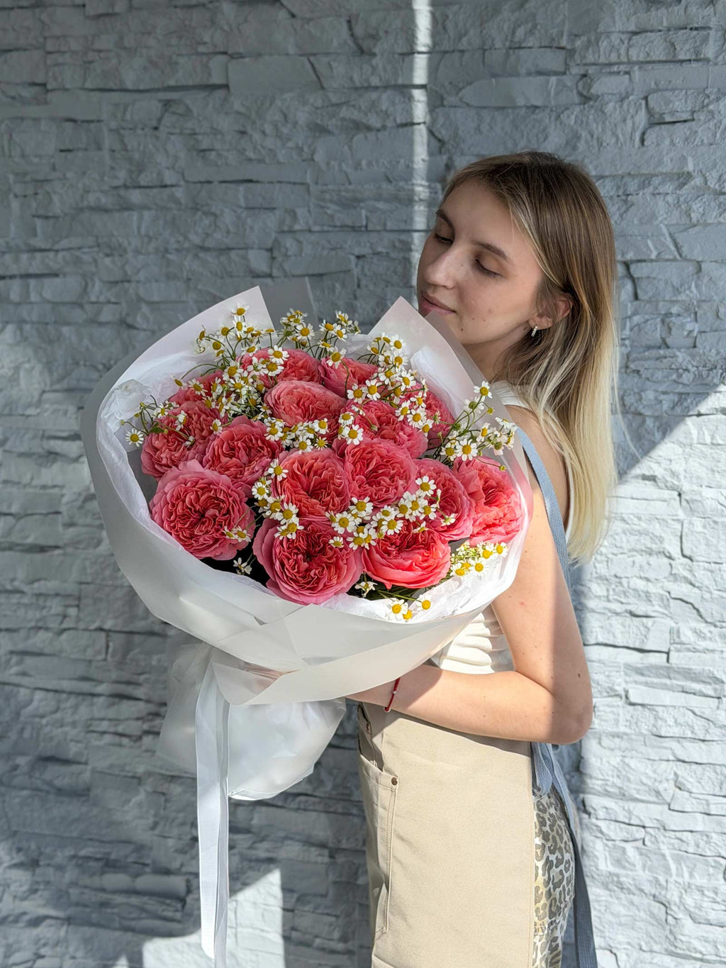 Woman holding the Garden Treasures bouquet made with garden roses and chamomile.