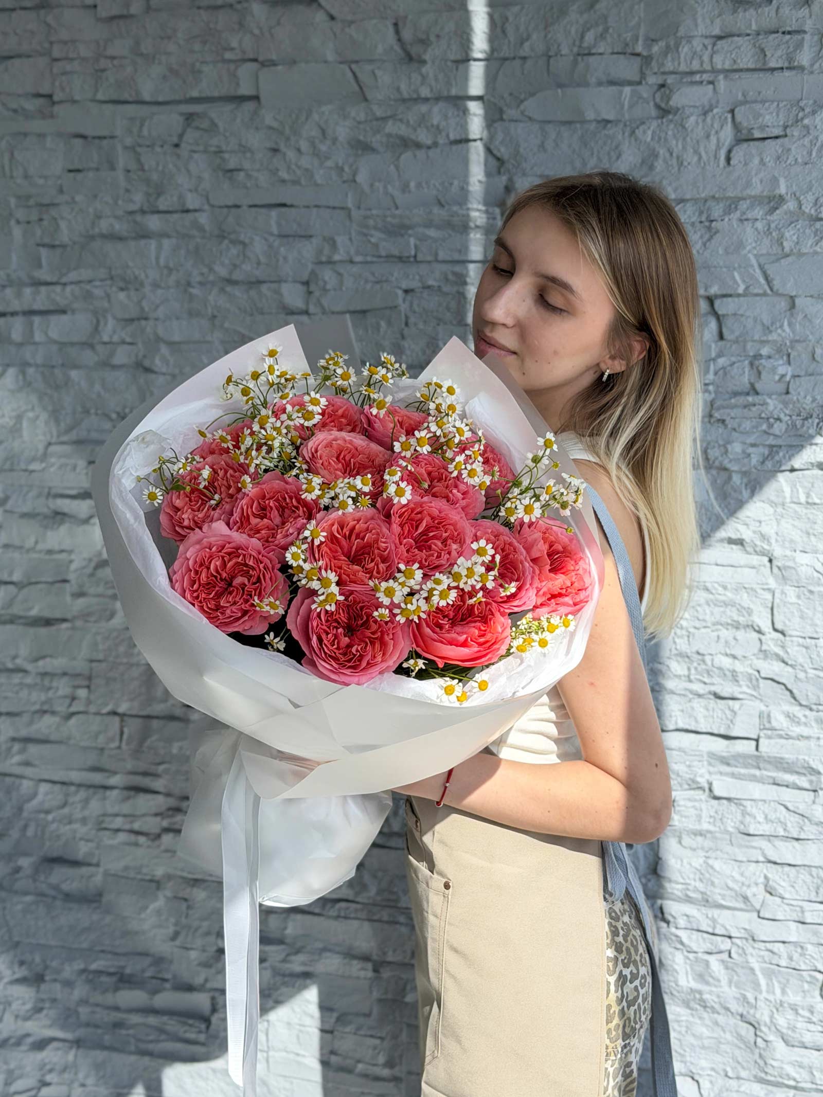 Woman holding the Garden Treasures bouquet made with garden roses and chamomile.