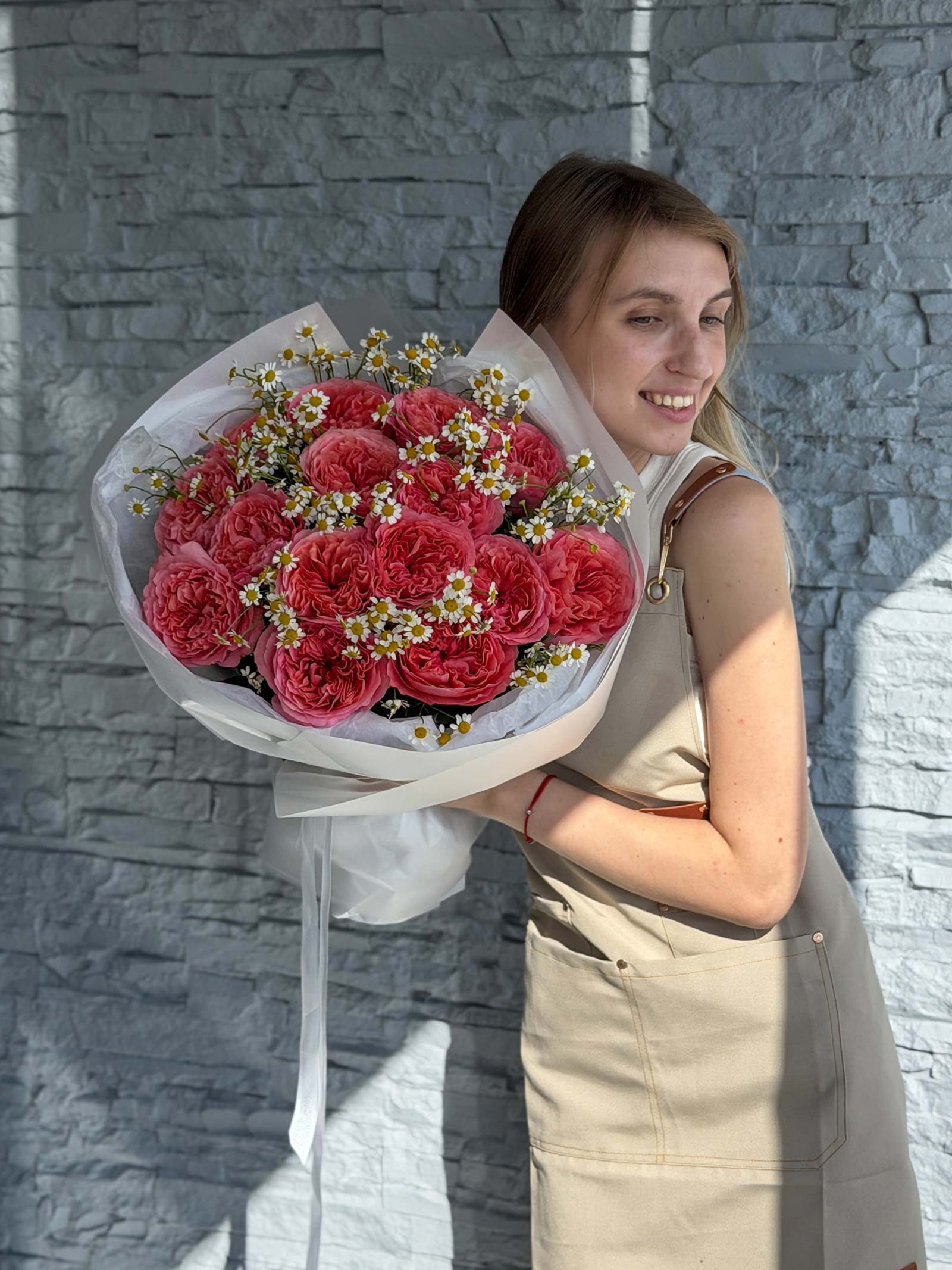 Woman holding the Garden Treasures bouquet with pink garden roses and delicate chamomile.