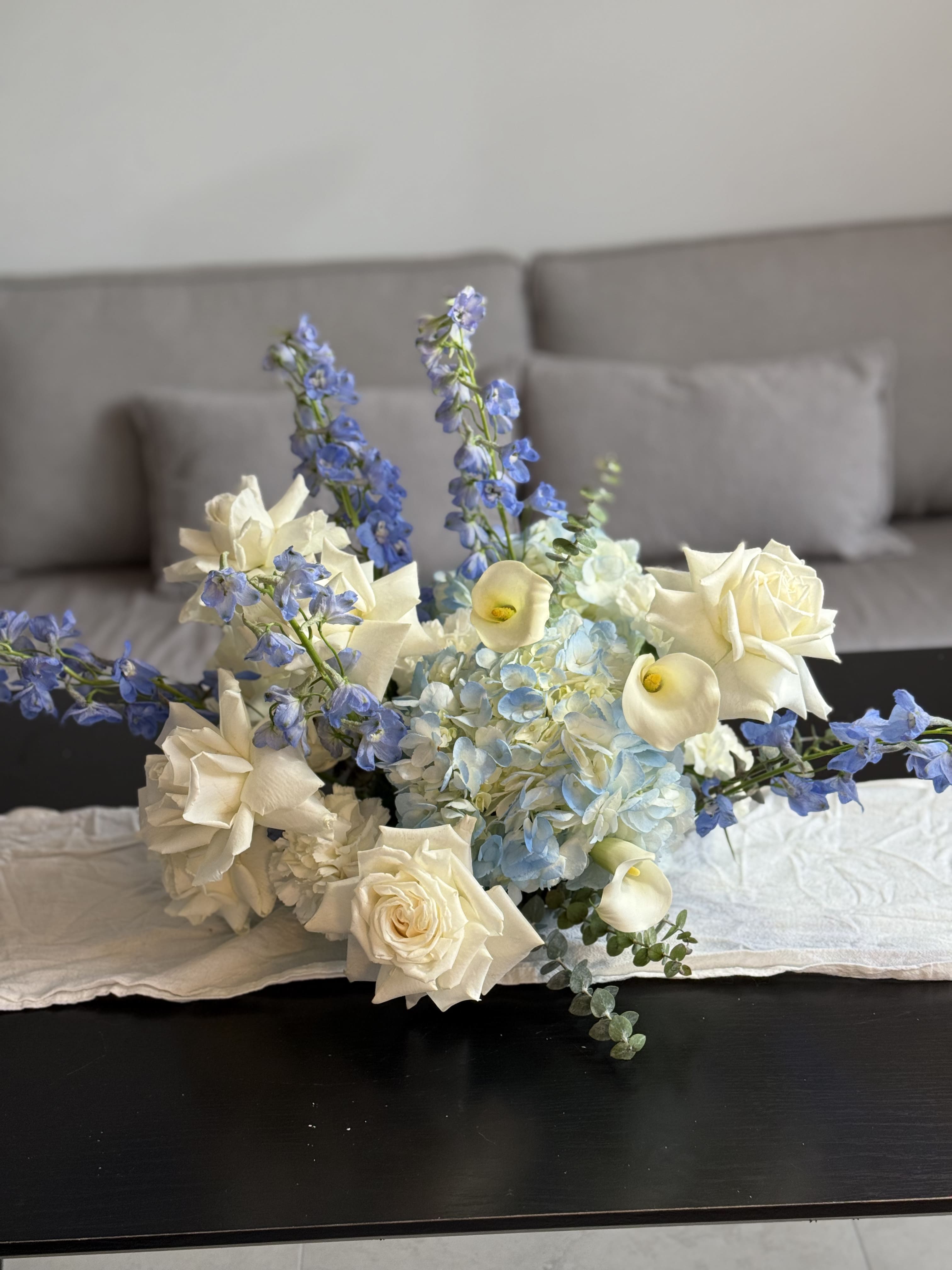 Floral arrangement with white and blue flowers on a table in a room.