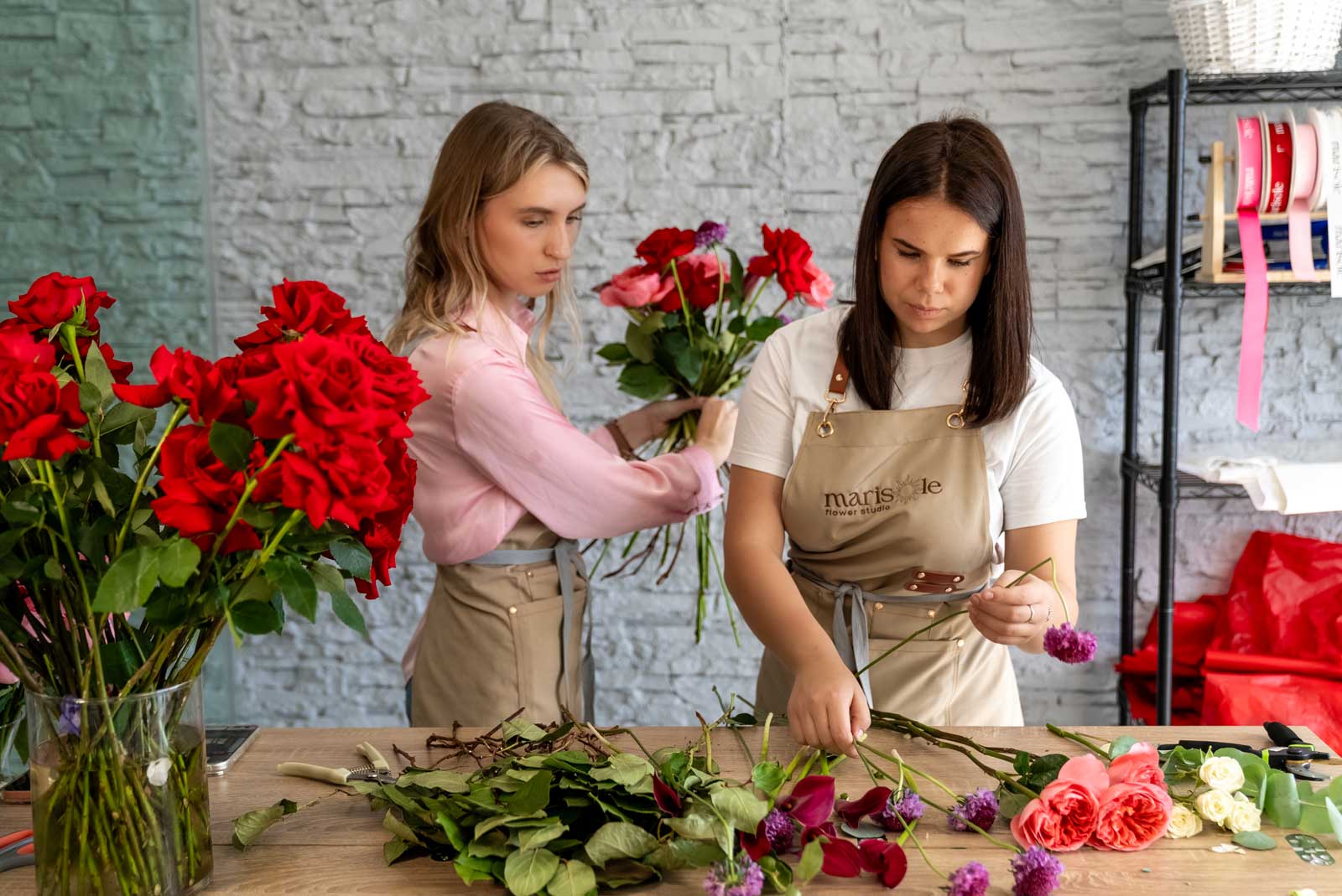 Two women working on floral arrangements in a studio setting.