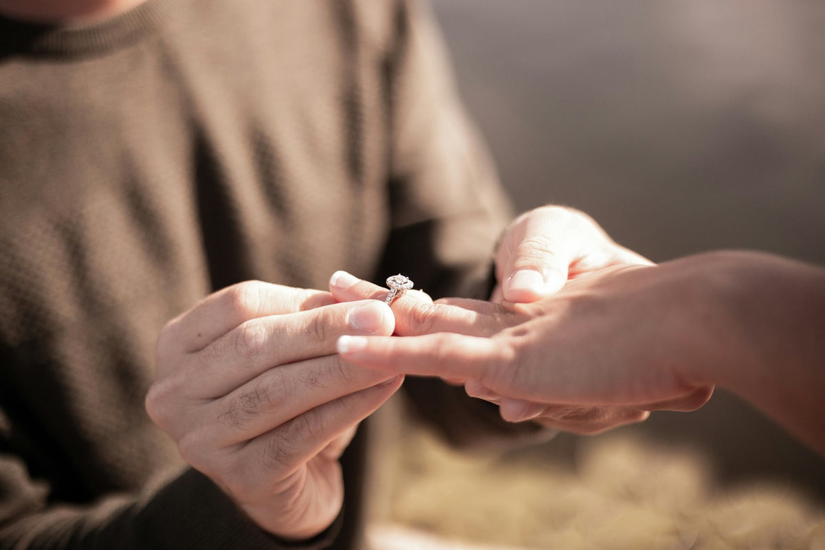 Person holding a diamond ring with a blurred background