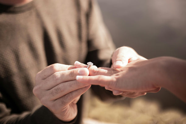 Person holding a diamond ring with a blurred background