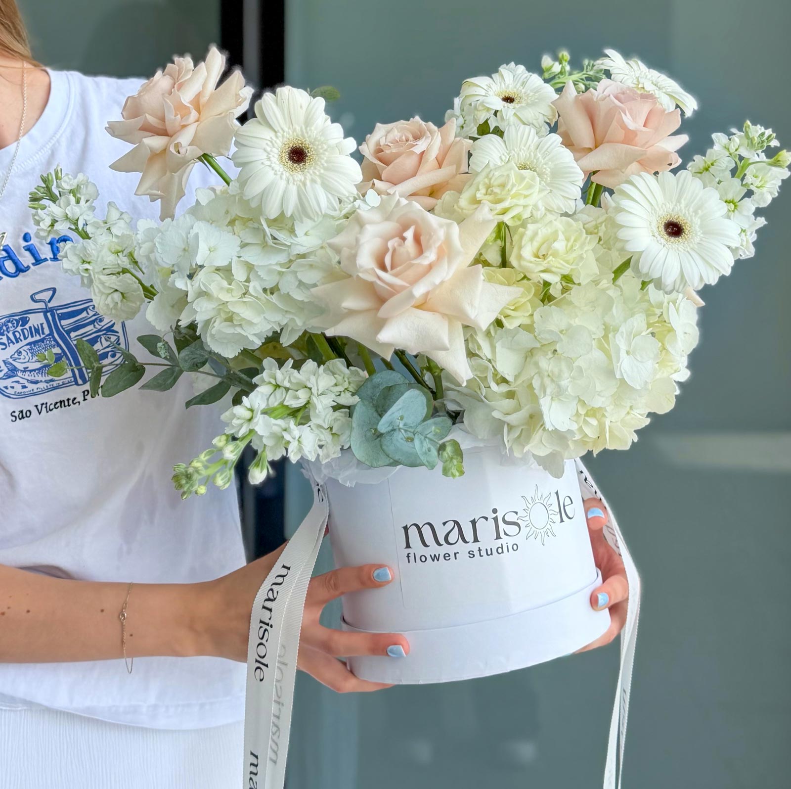 Person holding a bouquet of flowers in a 'marisole flower studio' box.
