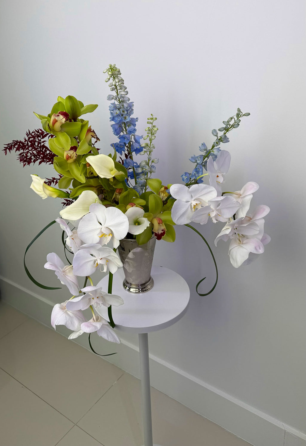 Floral arrangement on a small round table against a plain wall