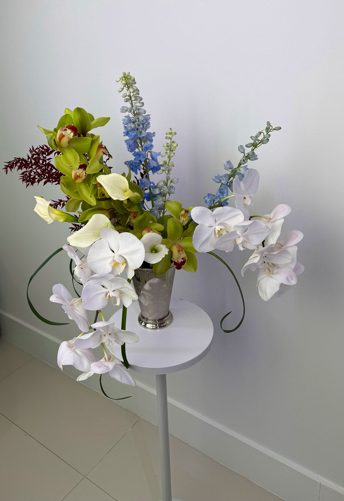 Floral arrangement on a small round table against a plain wall