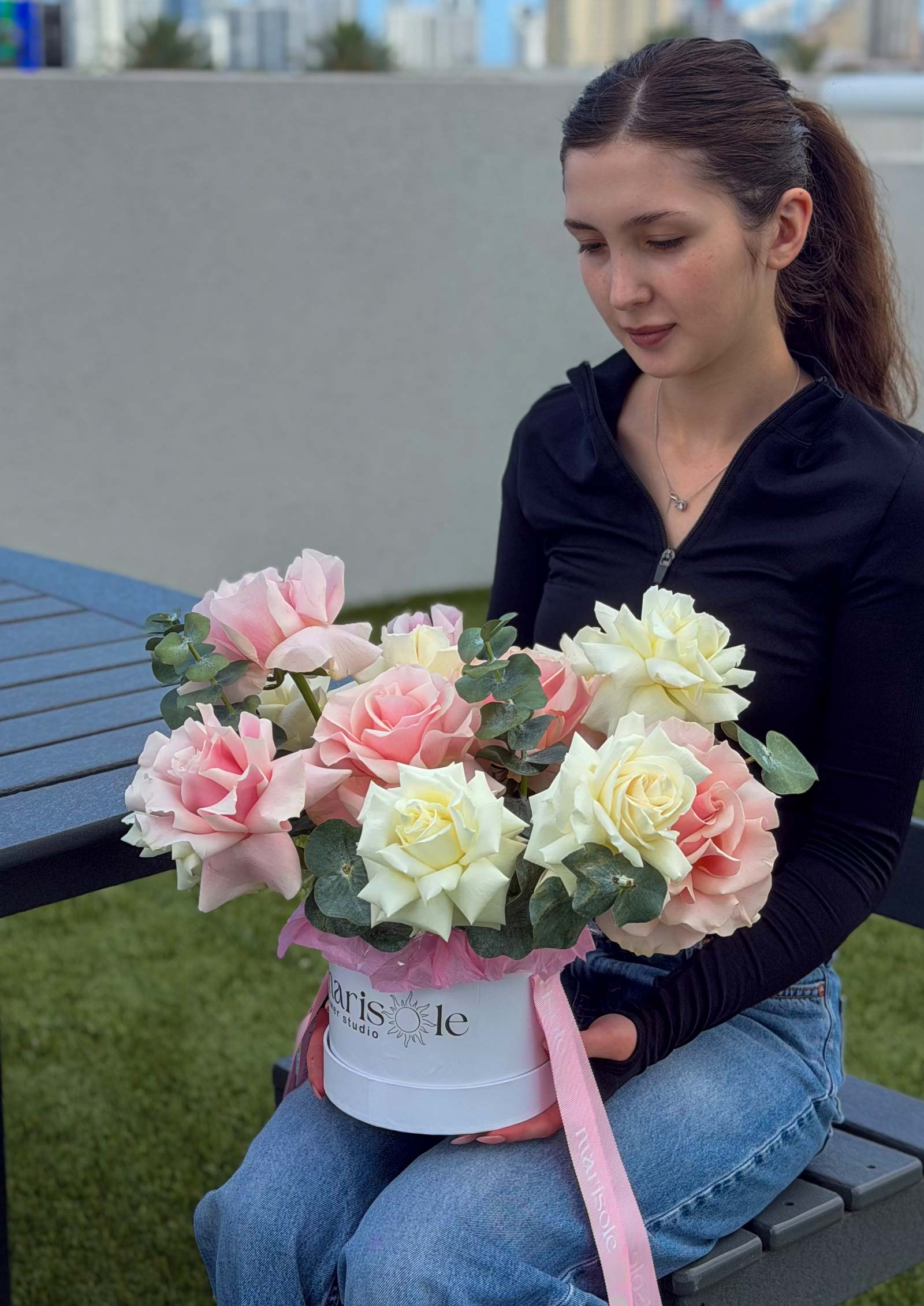 Woman holding the Pearl Bloom Box with blush and ivory French Roses and Eucalyptus in a Marisole Flower Studio box.