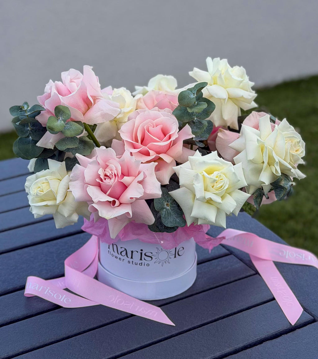 Pearl Bloom Box with blush and ivory French Roses and Eucalyptus placed on an outdoor table in a Marisole Flower Studio box.