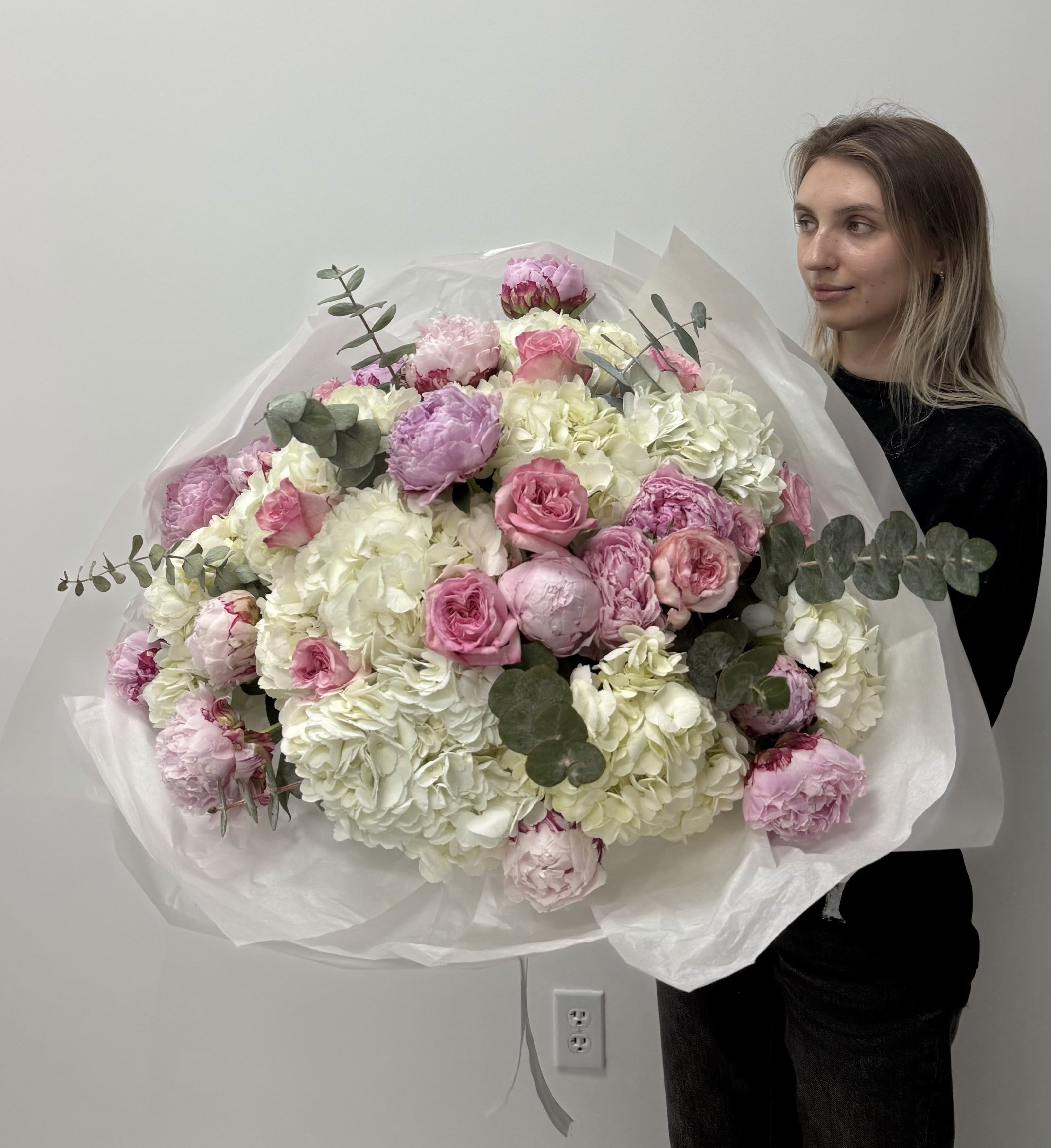 Person holding a large bouquet of flowers against a plain background