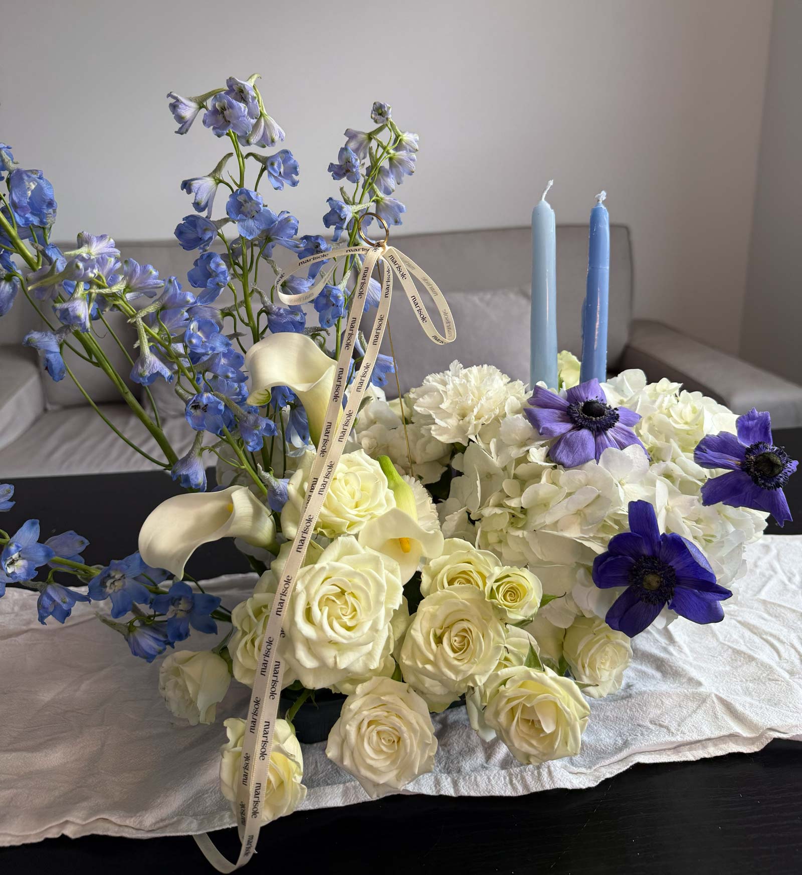 Bouquet of white and blue flowers with candles on a table.