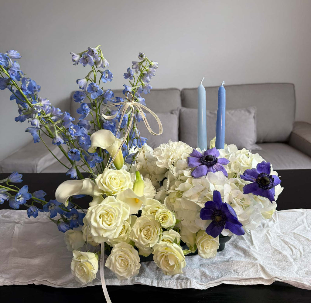 Floral arrangement with blue and purple flowers on a table in a living room setting.