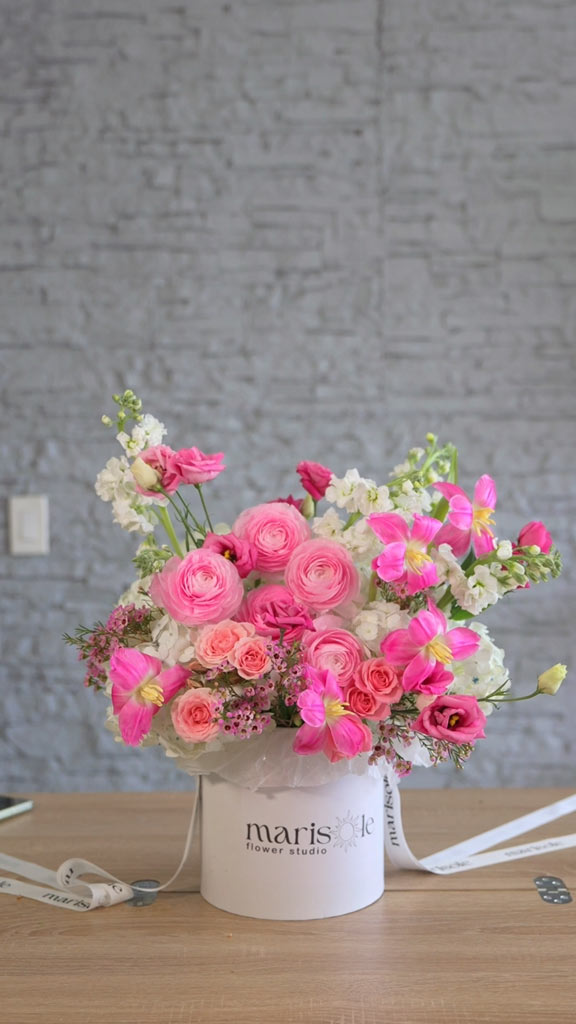 Pink flower box arrangement with pink ranunculus, roses, white stock, and bright pink tulips in a Marisole Flower Studio box.