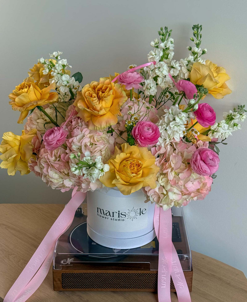 Pink Lemonade Box with yellow garden roses, pink ranunculus, blush hydrangeas, white stock, and chamomile in a Marisole Flower Studio box.