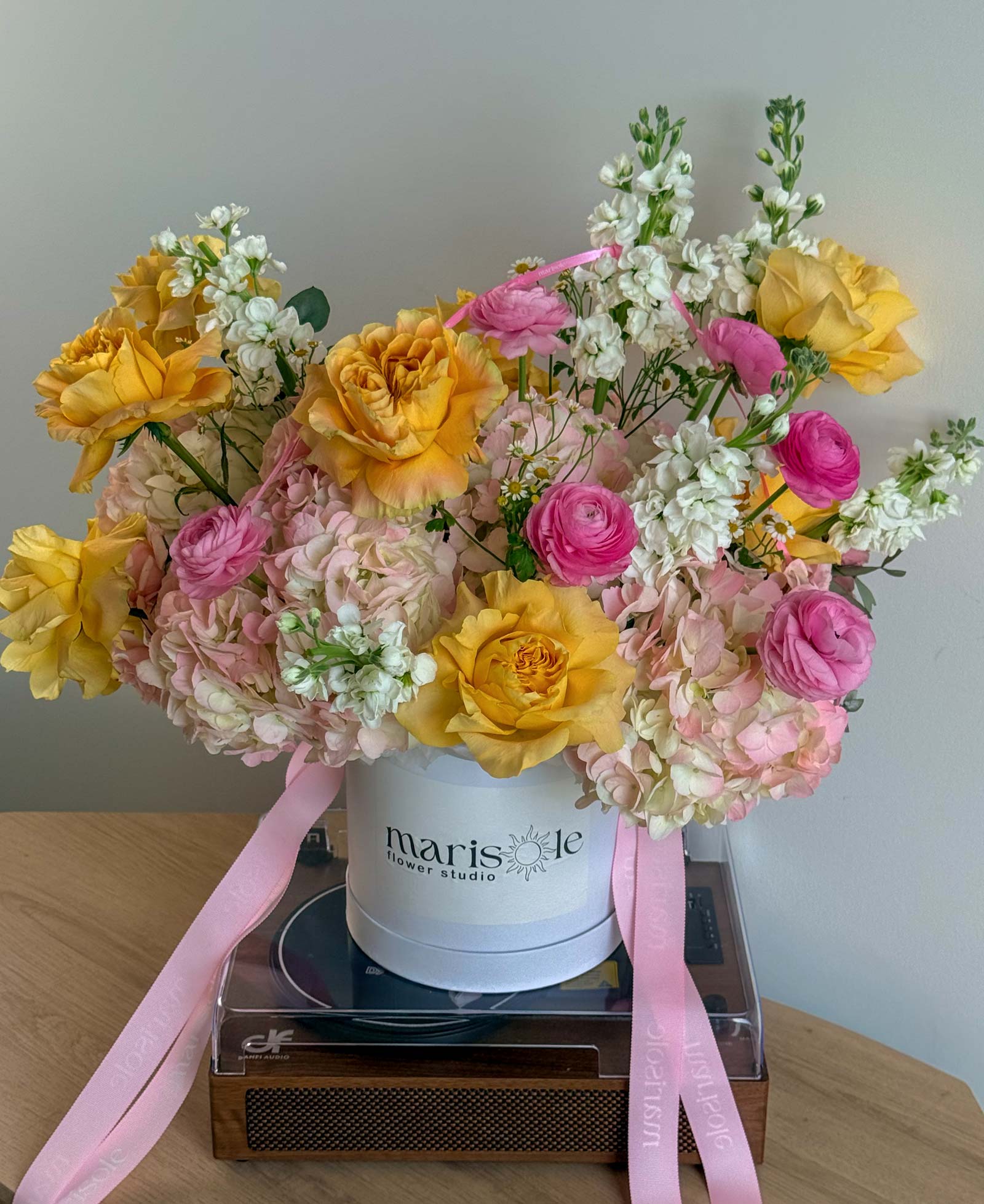 Pink Lemonade Box with yellow garden roses, pink ranunculus, blush hydrangeas, white stock, and chamomile in a Marisole Flower Studio box.